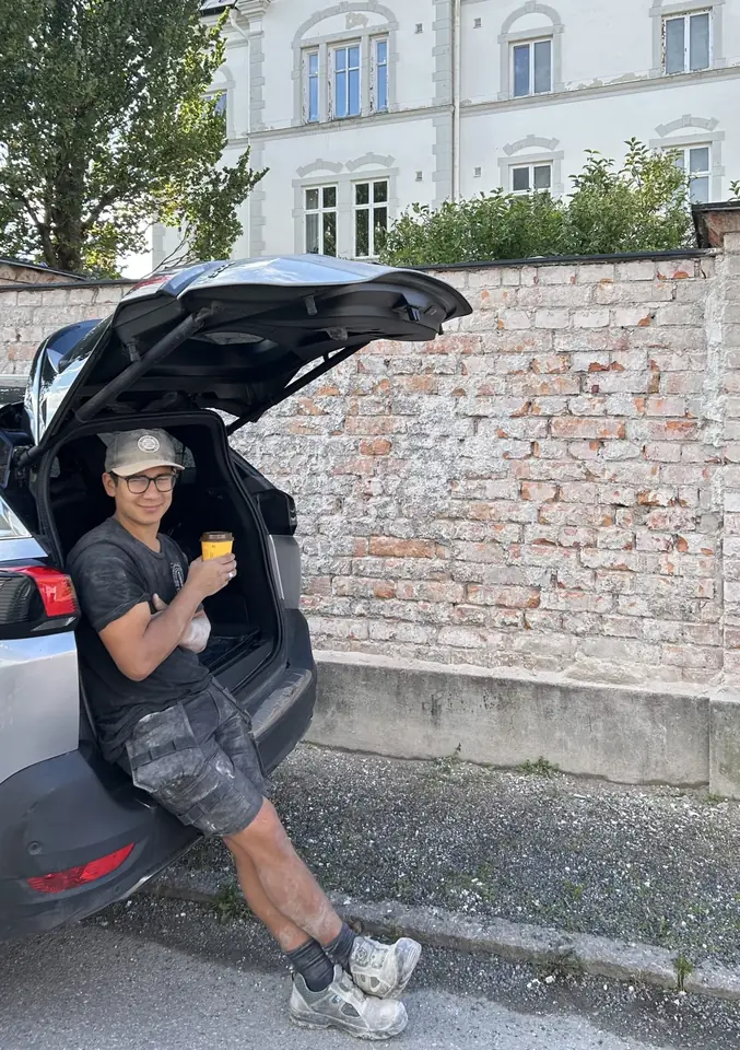Teodor Ramirez Givell sitter i bakluckan på en bil framför en tegelmur
